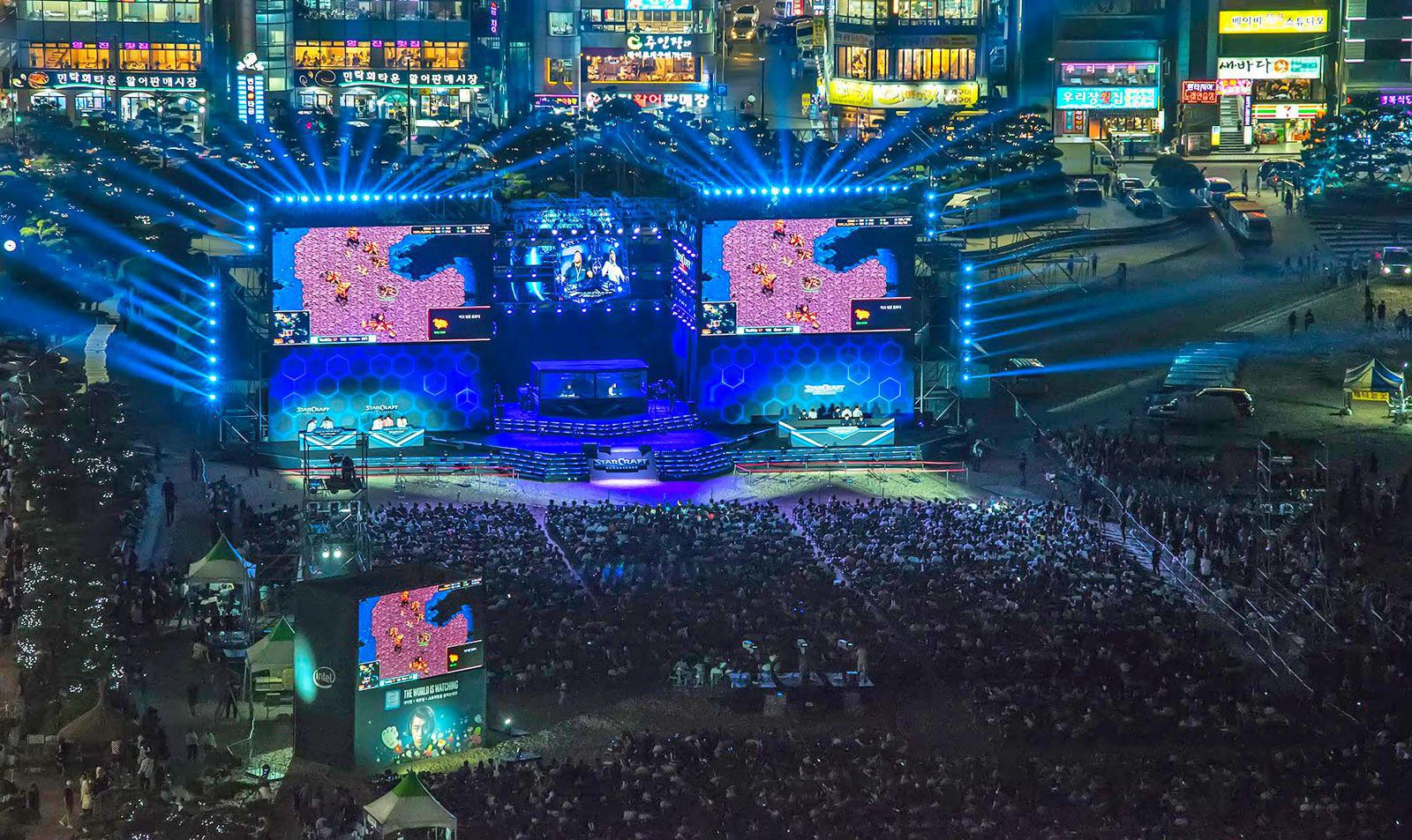 Nighttime scene of the StarCraft II finals in South Korea with giant screens and a packed crowd