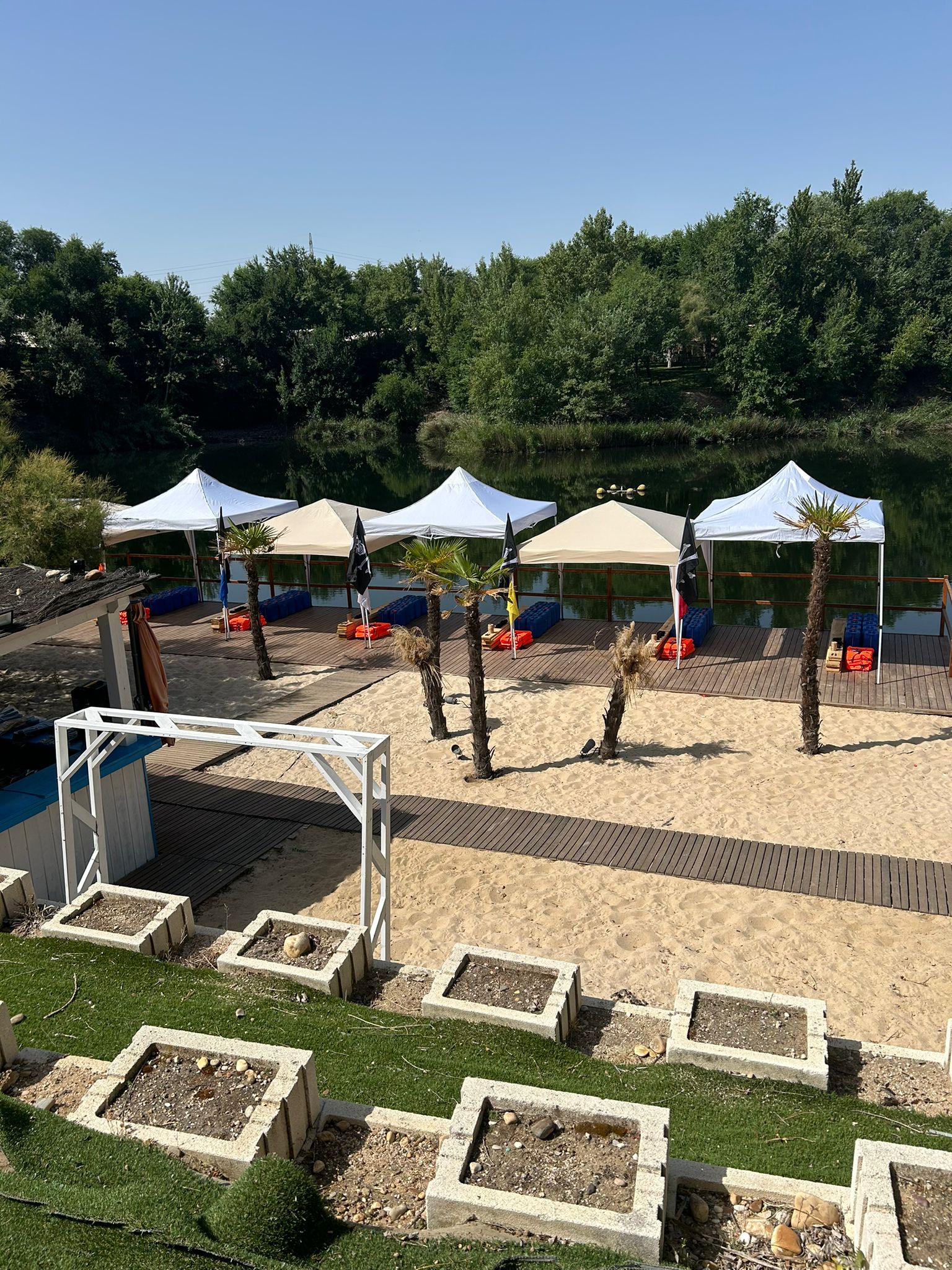 River beach with marquees and palm trees next to a lake, the setting for the team's summer party