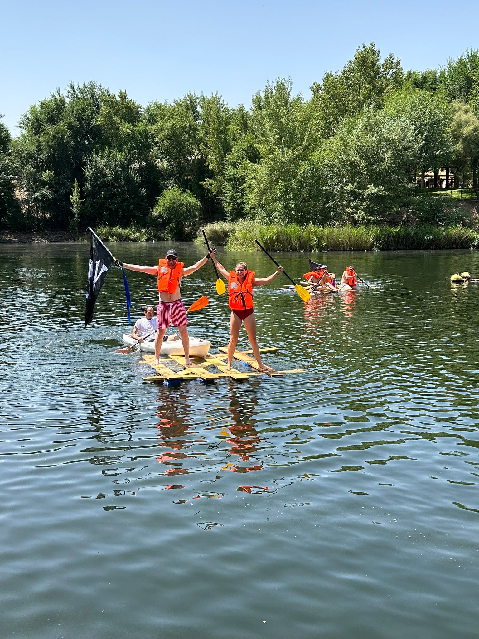 Two team members in life jackets celebrating on a homemade raft floating on the lake