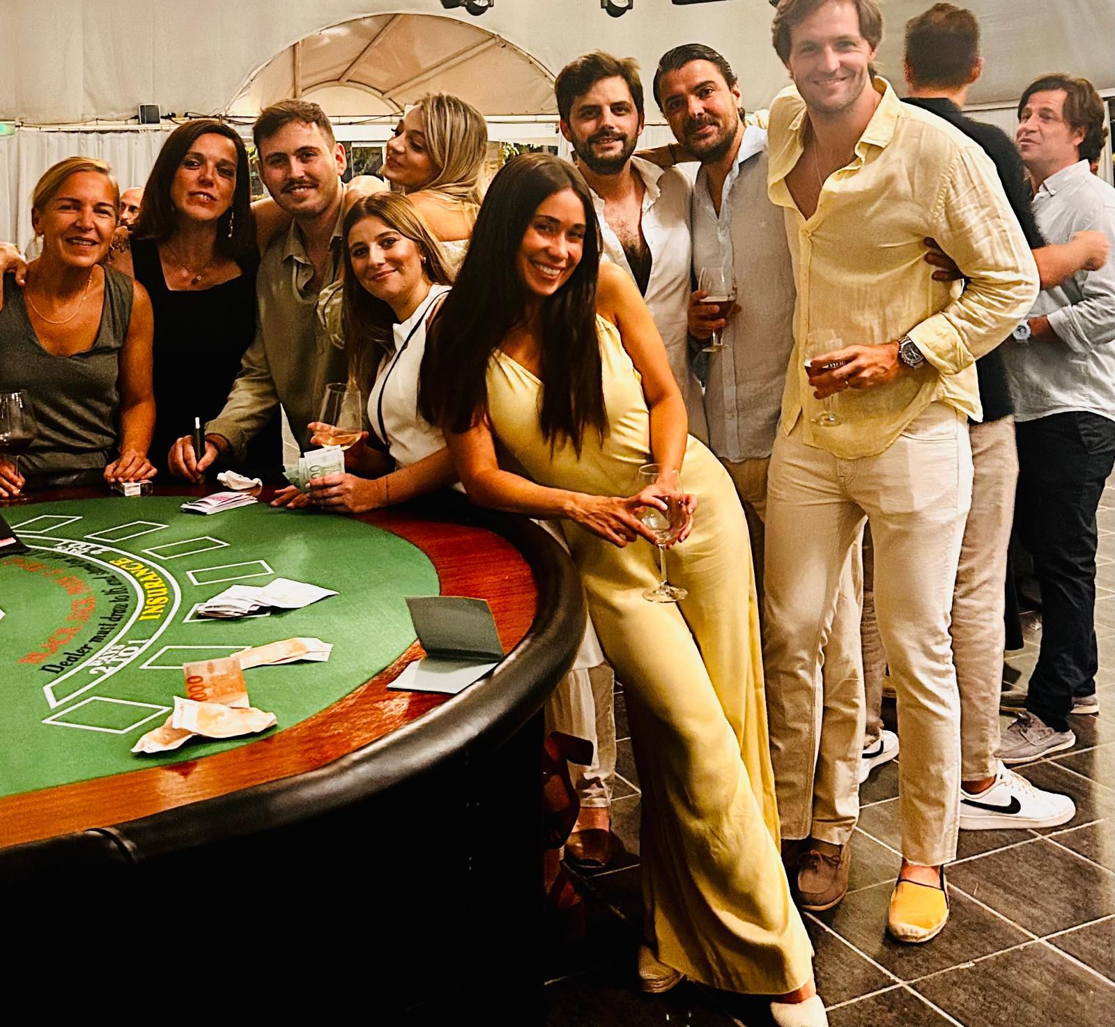 Team members posing and smiling next to a blackjack table at the casino-style party