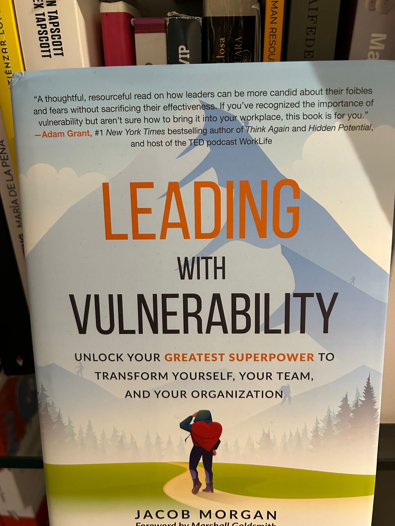 The book Leading with Vulnerability by Jacob Morgan with a hiker and a mountain