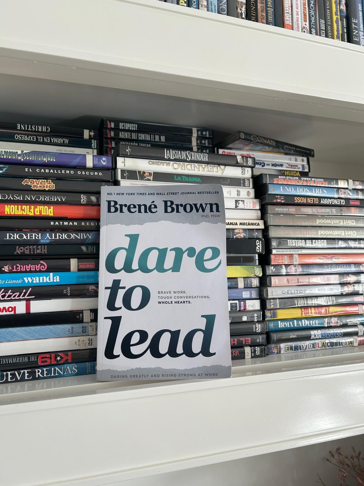 Dare to Lead by Brené Brown propped on a shelf alongside DVD movies