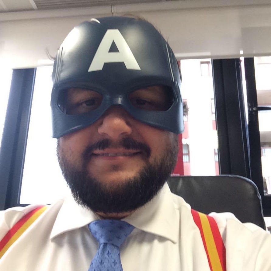Office selfie wearing a Captain America mask, shirt and red and yellow suspenders