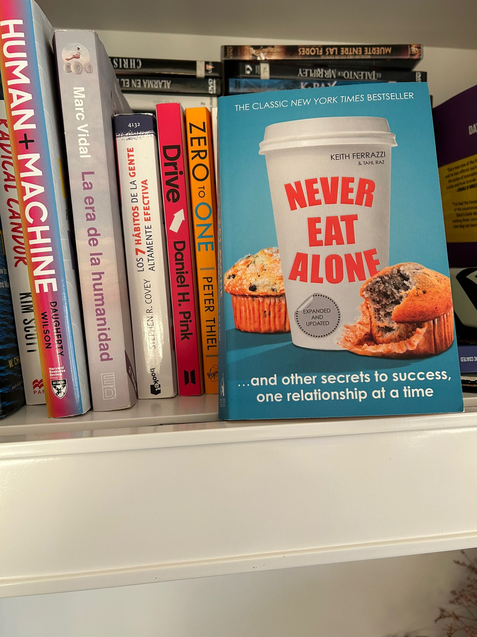 The book Never Eat Alone by Keith Ferrazzi on a shelf next to other business titles