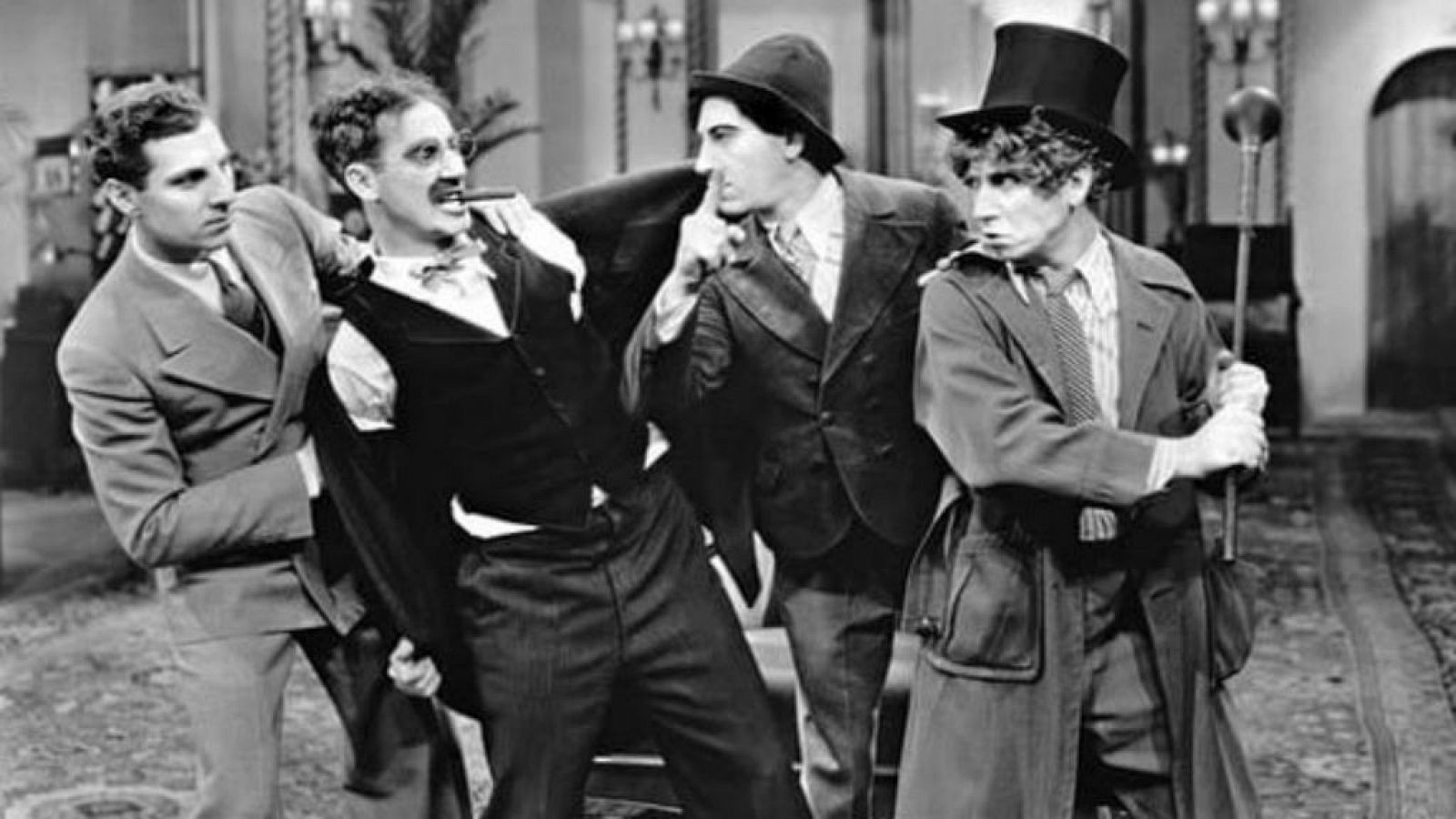 The four Marx Brothers in a hotel, with Harpo in a top hat, in a black-and-white scene