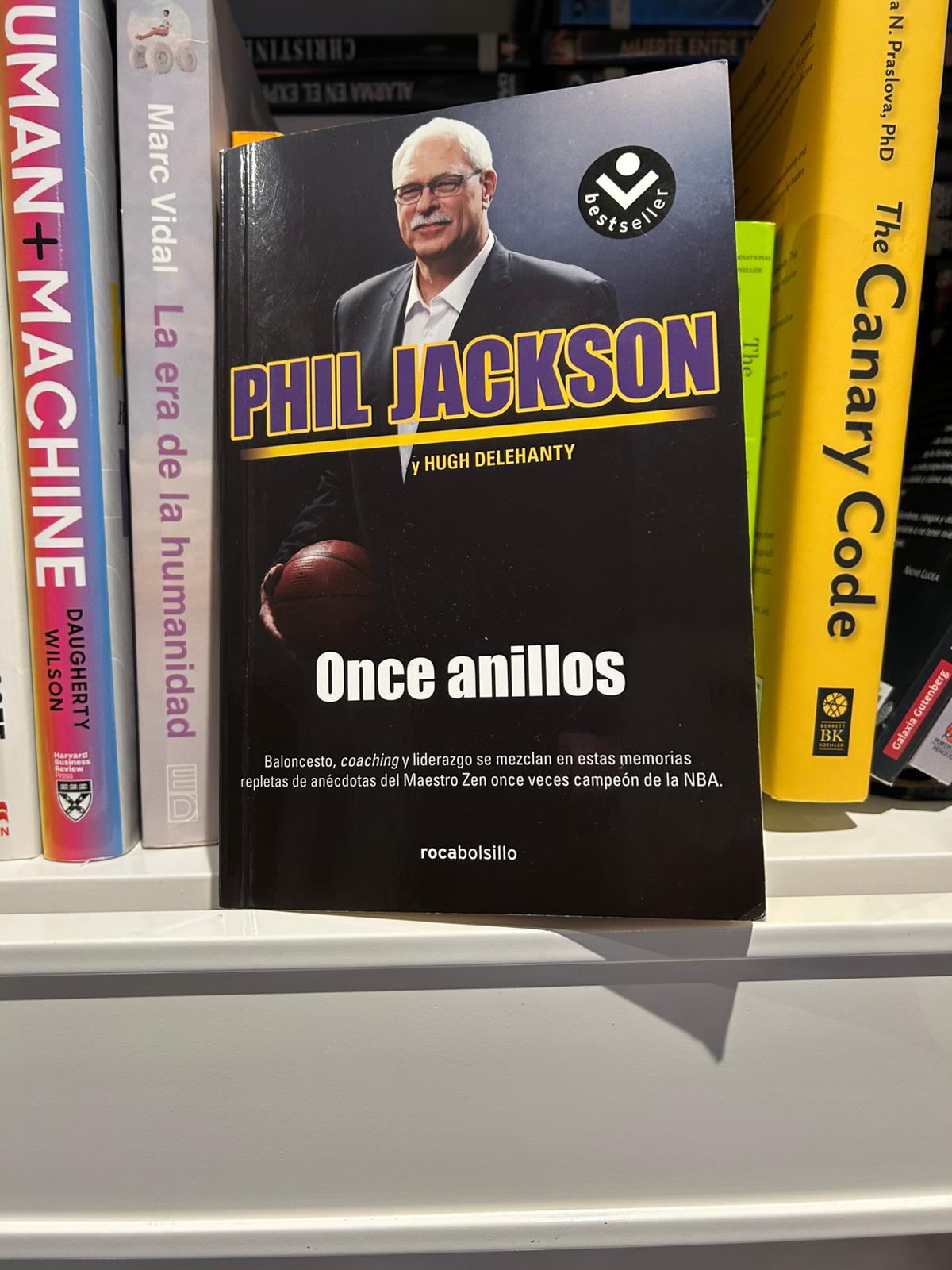 Phil Jackson's book Eleven Rings on a shelf next to other management titles
