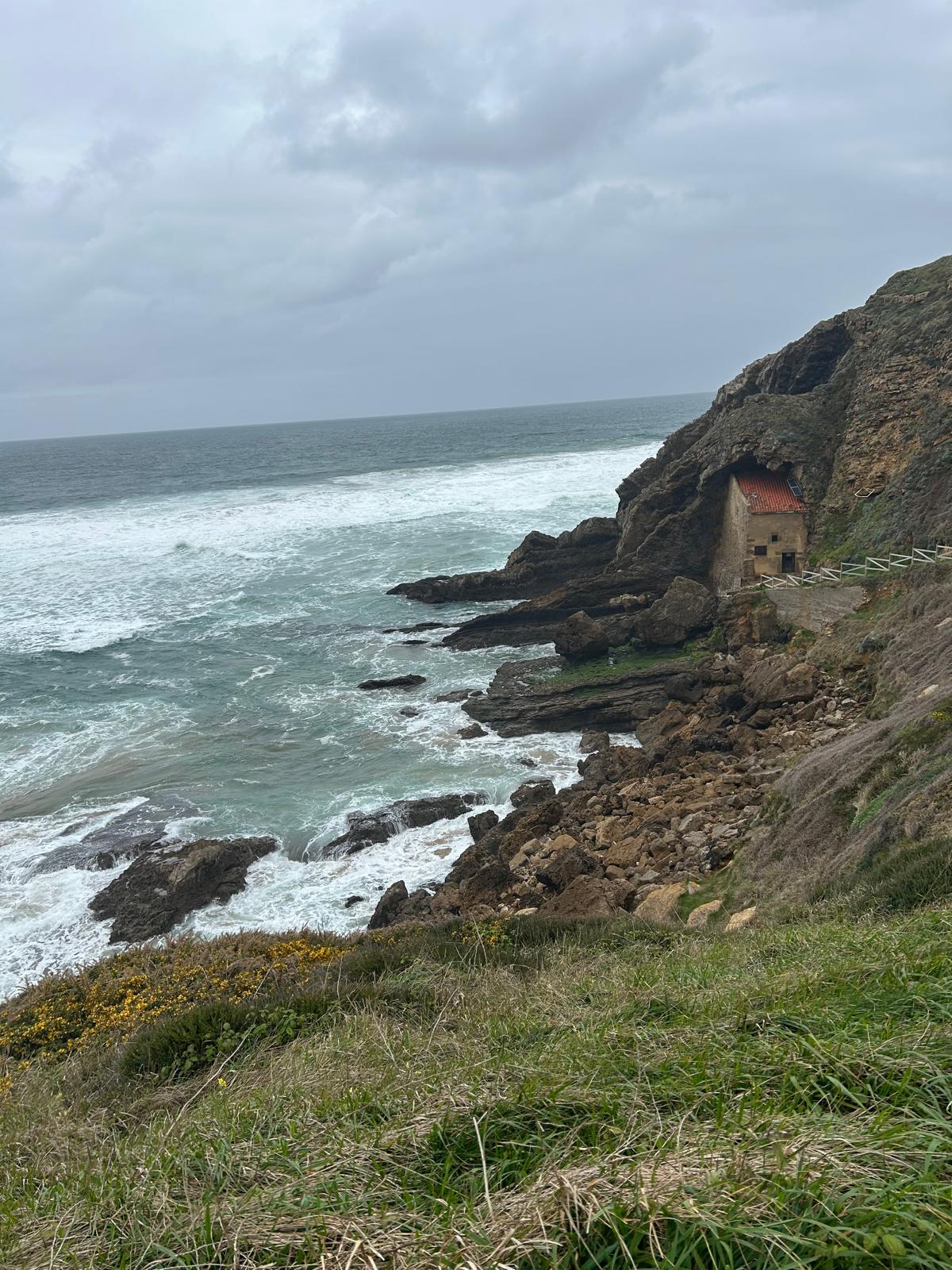 Santa Justa hermitage wedged into a cliff above the rough sea on the coast of Cantabria