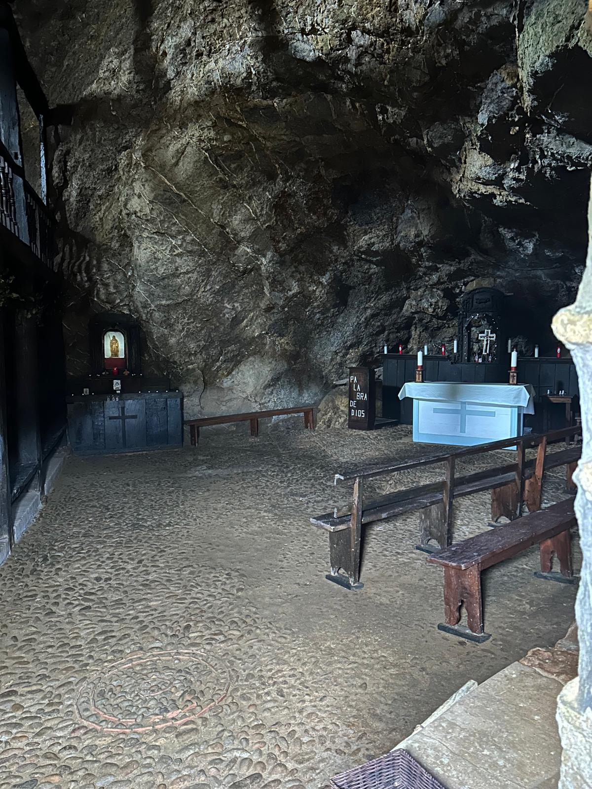 Rock-carved interior of the Santa Justa hermitage with an altar and wooden benches