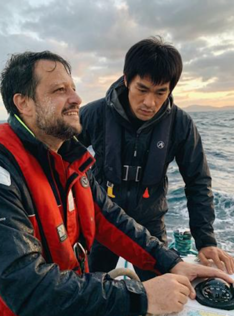 Two men in life vests on a boat at sunset over the sea